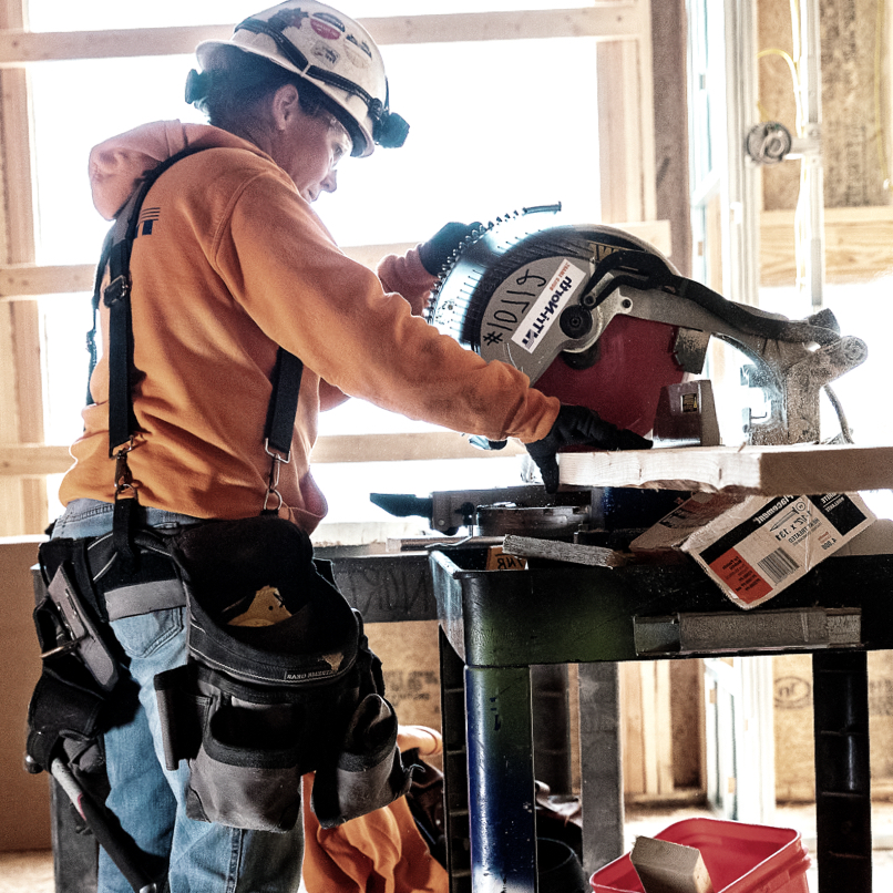 A member of Tri-North's construction crew cuts lumber using a circular saw.