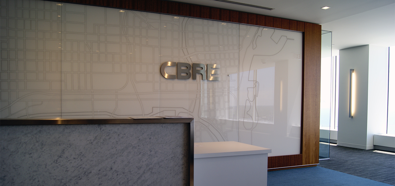CBRE building reception area with logo and map behind desk as built by Tri-North Builders in Wisconsin.