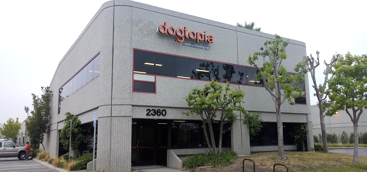 The Dogtopia logo can be seen at the top of a two-story building housing a Dogtopia location.