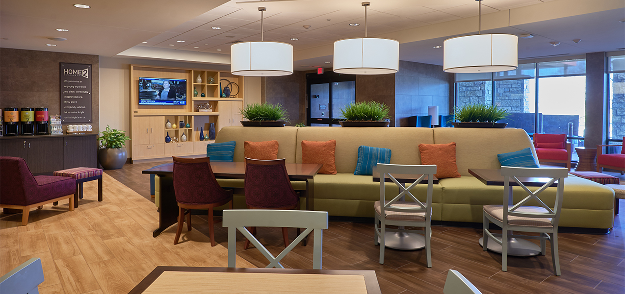 Sitting and lounge area with tables and chairs inside the Home2Suites by Hilton Madison in Wisconsin.