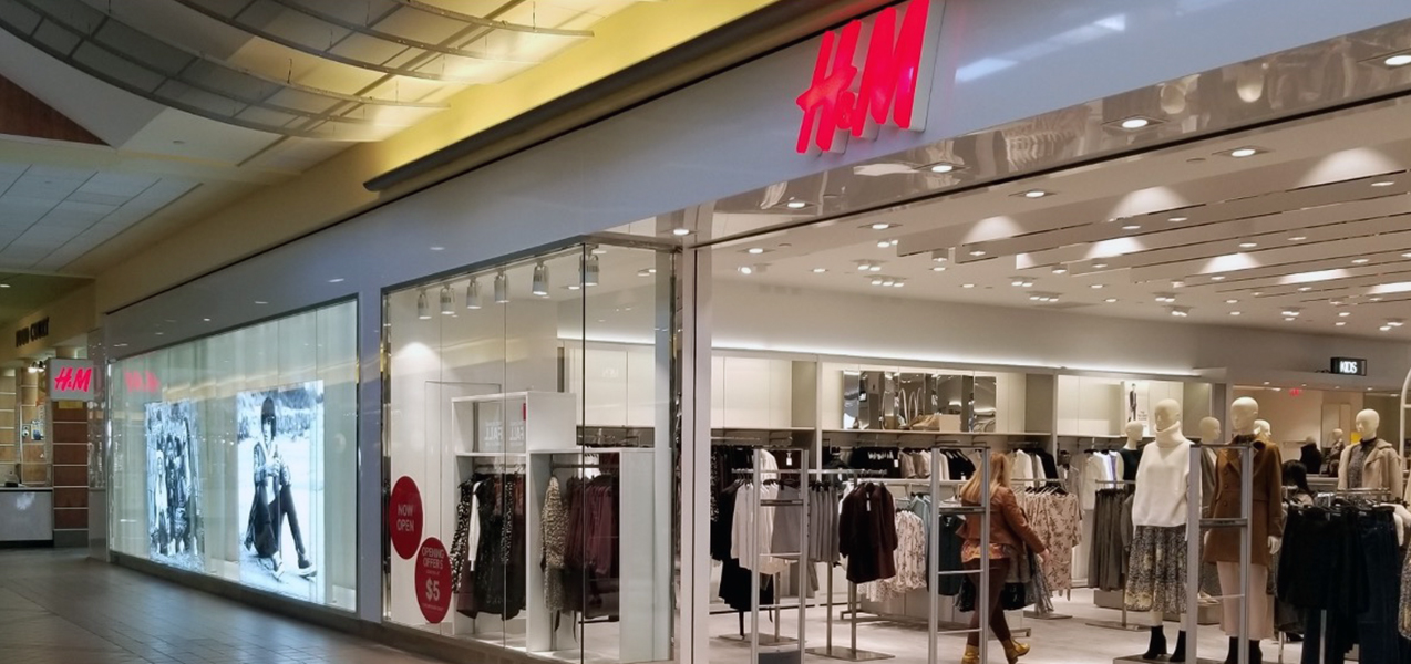 Large photographs and racks of clothing are featured in the windows of this H&M store location.
