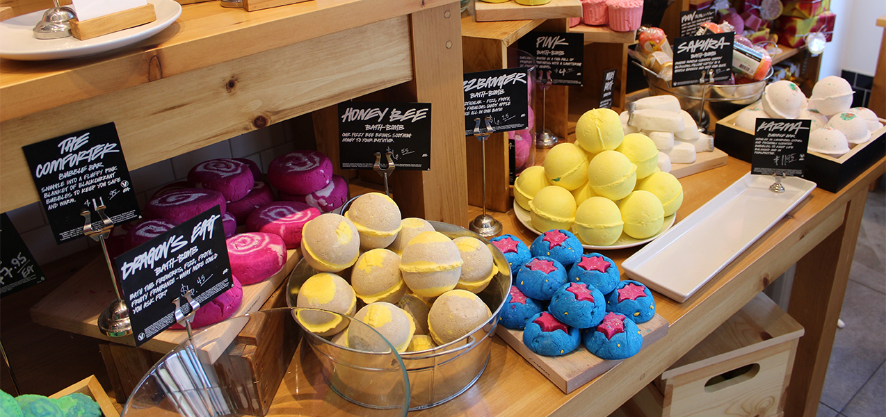 Bath bombs fill a wooden table at a Lush retail store, a Tri-North project.