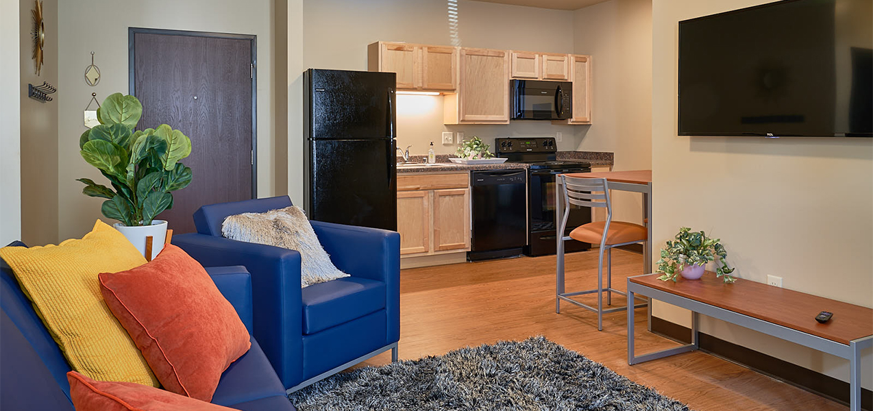 Living room area showing kitchen inside Tri-North Builders remodeled student housing apartments at Newman Heights.