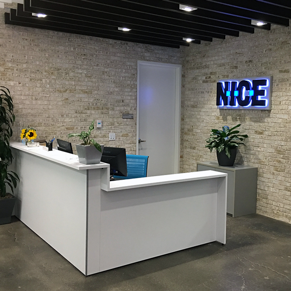 The reception desk and glowing sign welcome visitors to NICE, a Tri-North building.