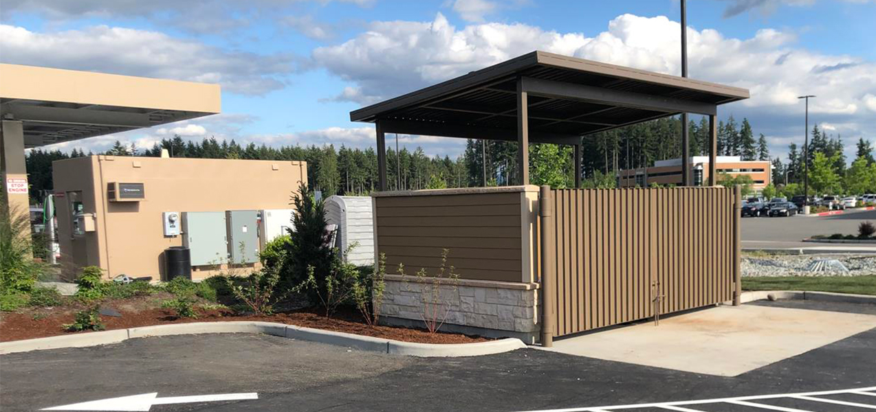 An open-air structure conceals dumpsters in the parking lot of Valvoline Instant Oil Change.