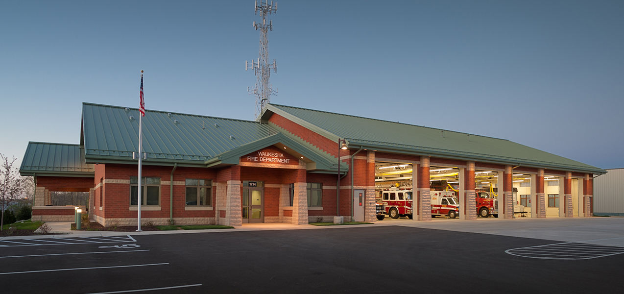 Front entrance, garage doors, of Waukesha Fire Department at night showcasing work by Tri-North Builders.
